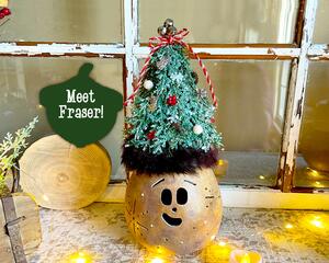 This is a whimsical Christmas elf made with a real dried gourd. This elf's name is Fraser. His face is carved into the round gourd shell. 